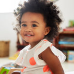 baby with curly hair smiling